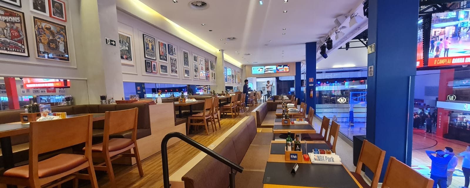 Restaurante do NBA Park com vista, pelo vidro, para a quadra de basquete iluminada do parque